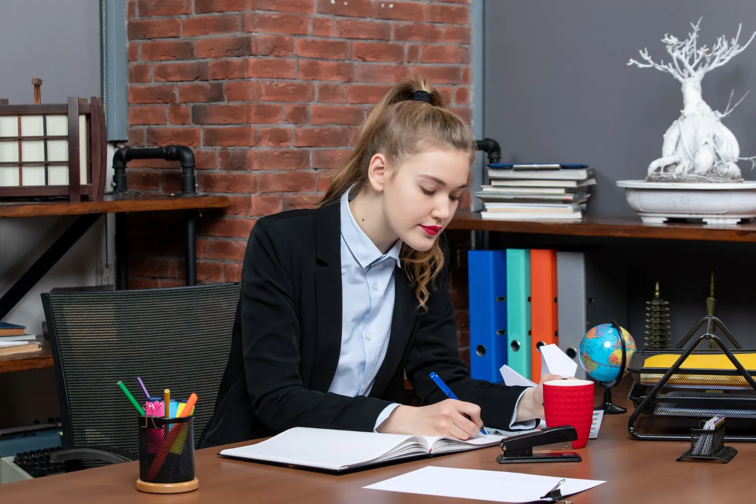 An attentive young professional takes notes, exemplifying the preparation for job interviews as advised by JOH Partners' essential interview guidelines.
