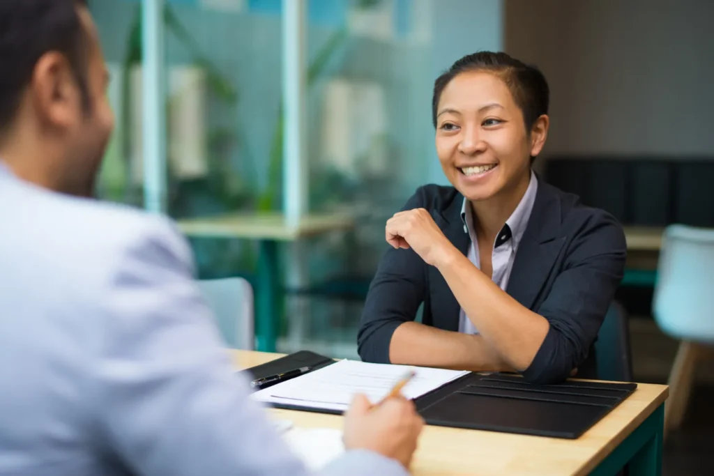 A woman in a business meeting, smiling confidently as she makes a positive first impression, as advocated by JOH Partners.