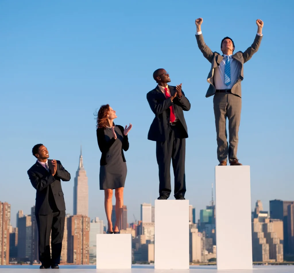 Three professionals on podiums against the backdrop of a city skyline, with the tallest figure cheering in victory, illustrating career success as discussed in JOH Partners' article on envisioning one's future.