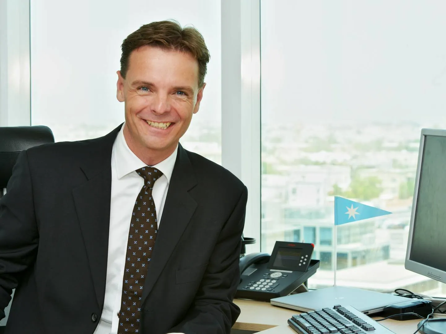 Christian Nyholm, in business attire, sits in an office, representing strategic leadership and organizational trust, themes discussed by JOH Partners.