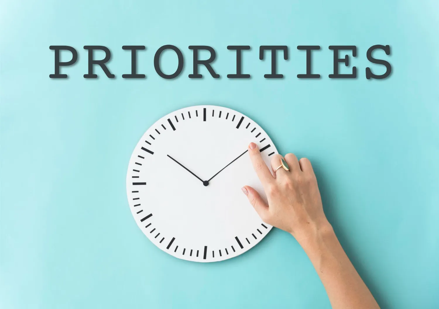A hand adjusting a minimalist clock with the word 'PRIORITIES' above it, symbolizing the importance of time management for productivity, as featured in JOH Partners' blog on effective time management strategies.