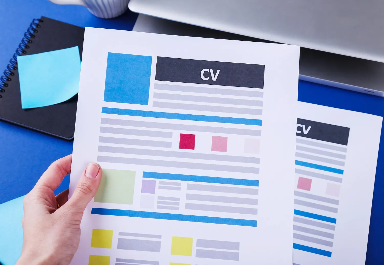 Close-up of a hand holding a colorful, well-organized CV. Learn valuable resume crafting tips with JOH Partners to impress potential employers.