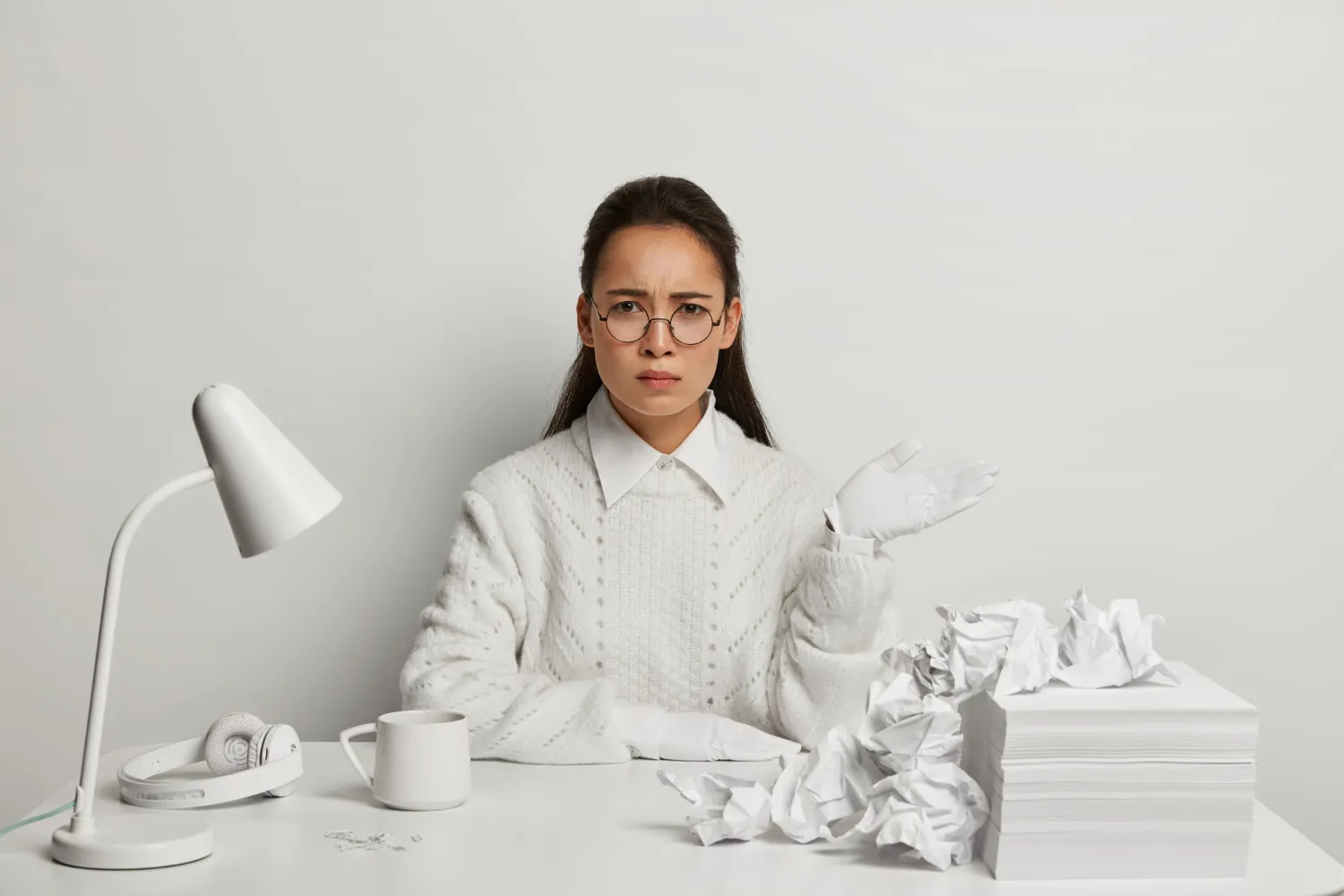 Woman with a perplexed expression surrounded by crumpled papers at her desk, symbolizing common resume mistakes highlighted in JOH Partners' blog.